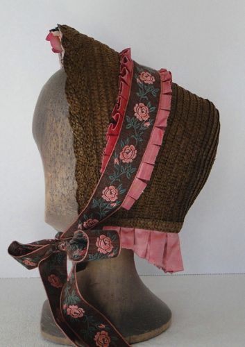 The front of the bonnet is finished with a braid of straw made from the strips used for the body.  The band is made of floral ribbon and pleated silk.
